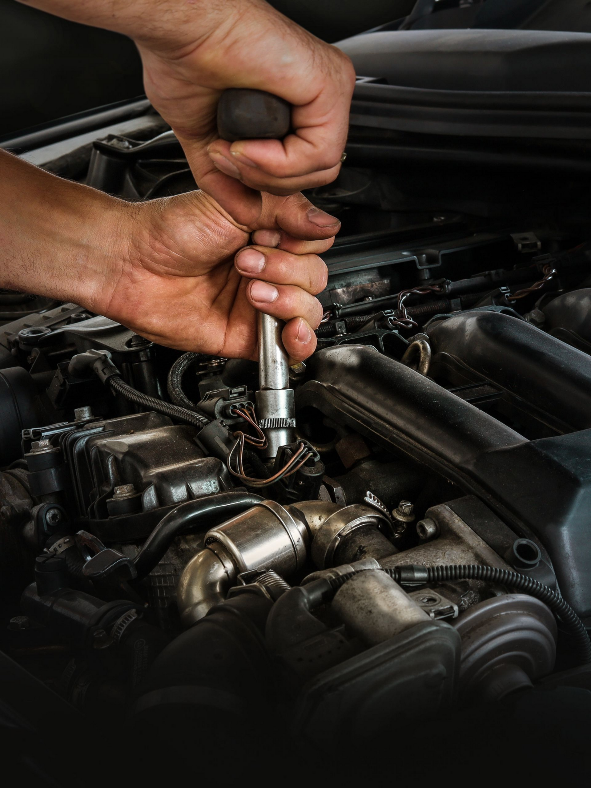 Gros plan sur les mains d'un mécanicien intervenant sur un moteur
