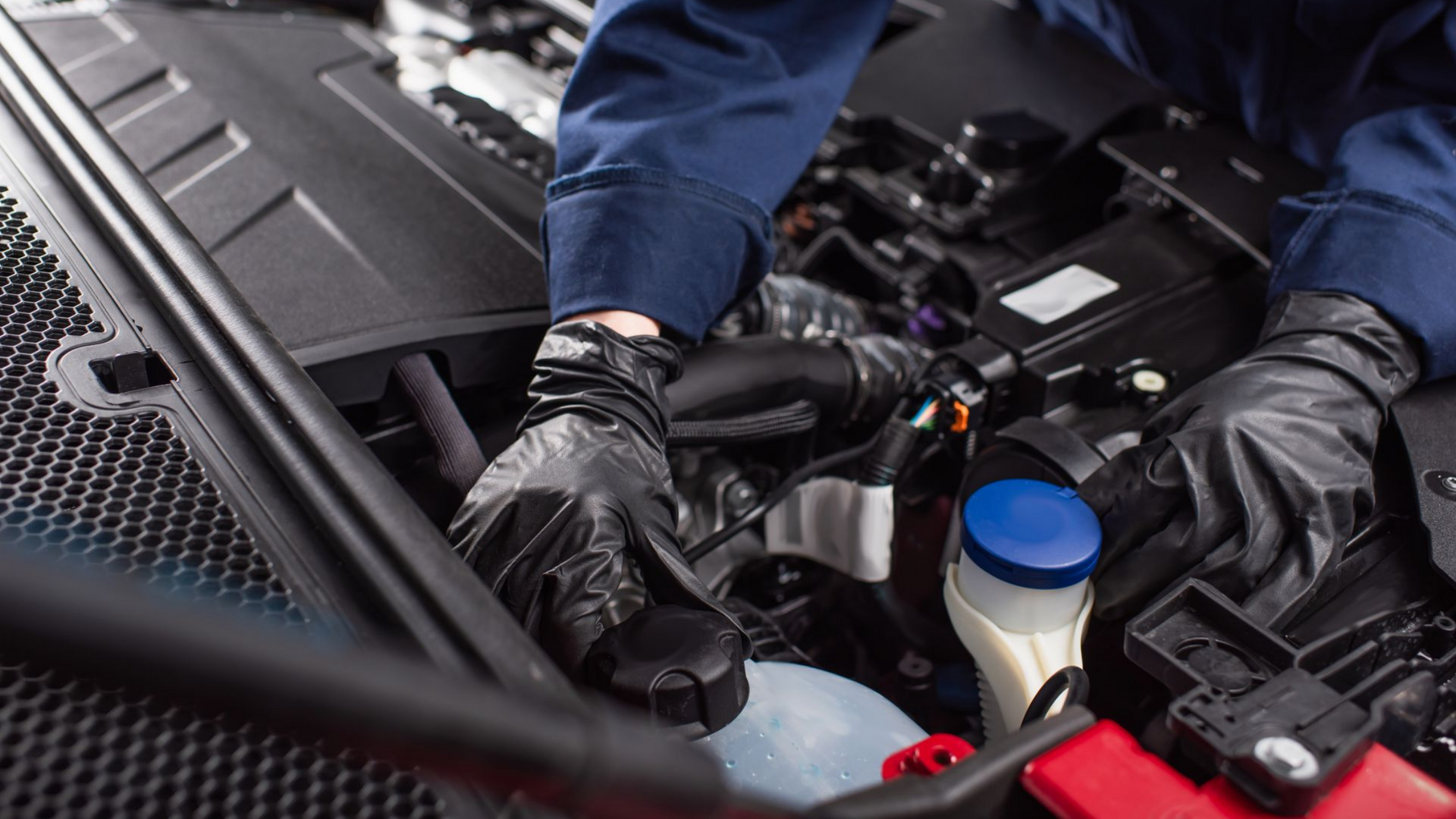 Mécanicien portant des gants et travaillant sur un moteur de voiture