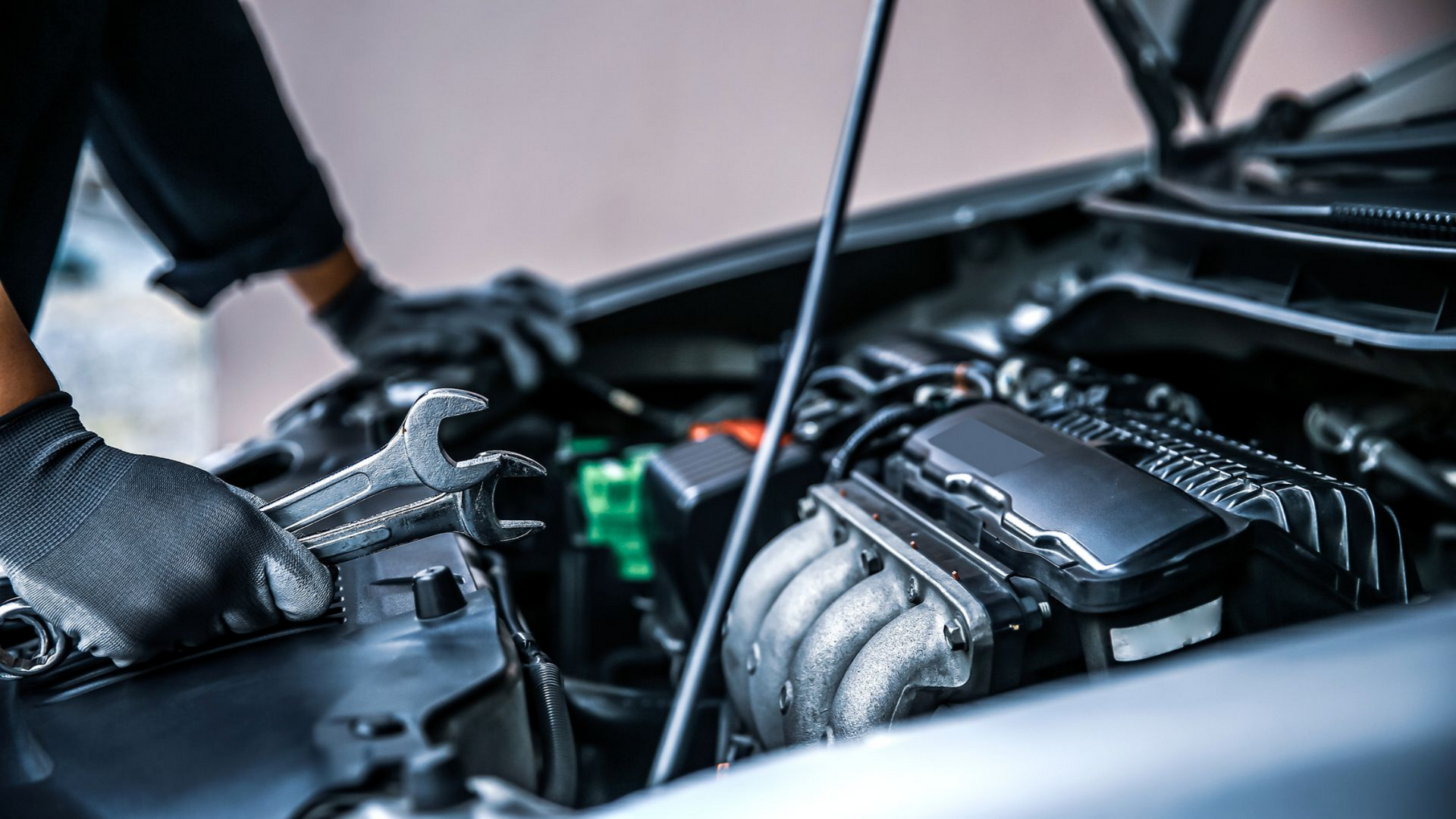 Mécanicien tenant des clés à molette et penché sur un moteur