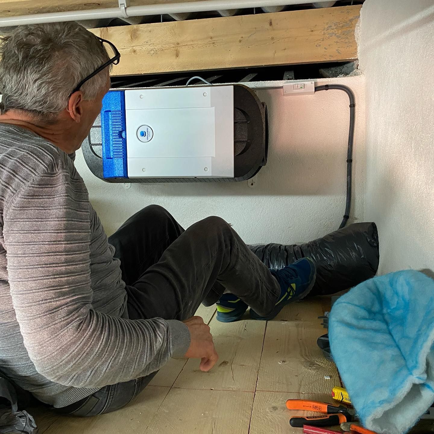 Installation d'une ventilation par un artisan assis