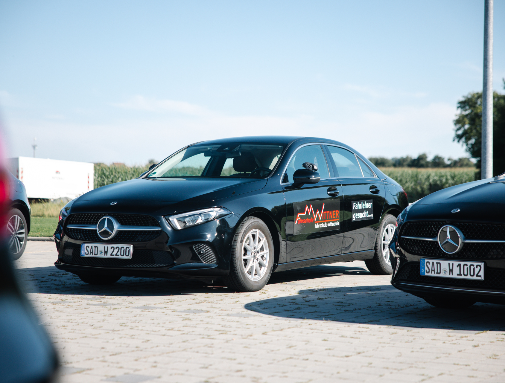 Schwarze Autos parkten in einer Reihe, eines davon mit dem Logo „Fahrschule Wittner“.