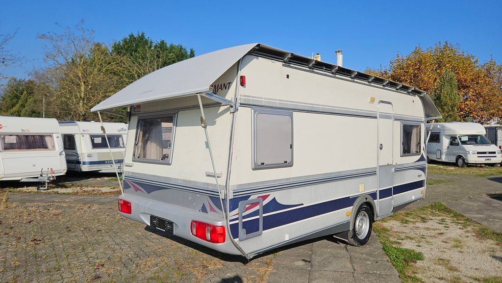 Une remorque blanche et bleue avec un auvent est garée sur un parking.