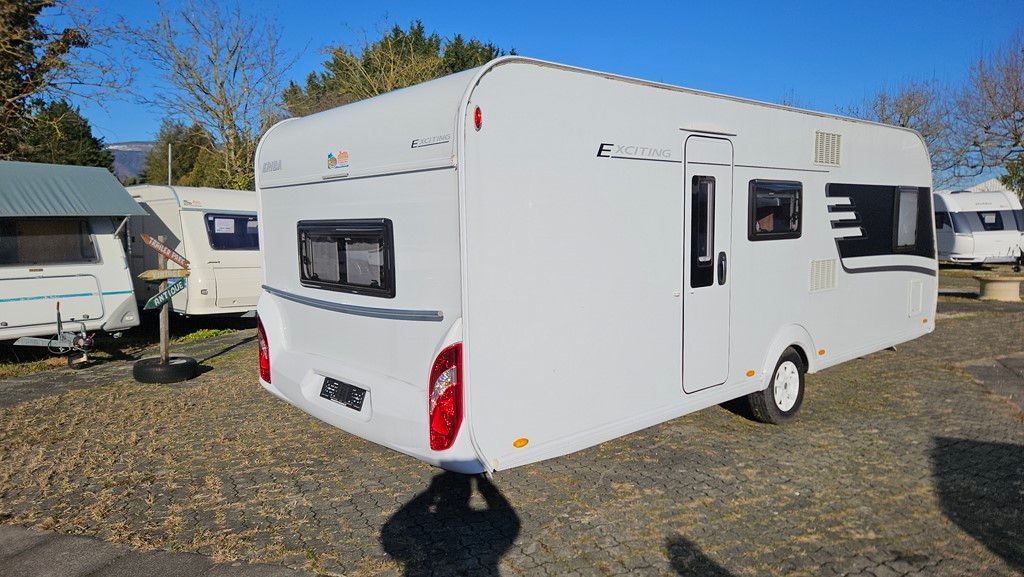 Un camping-car blanc est garé sur un terrain en gravier.
