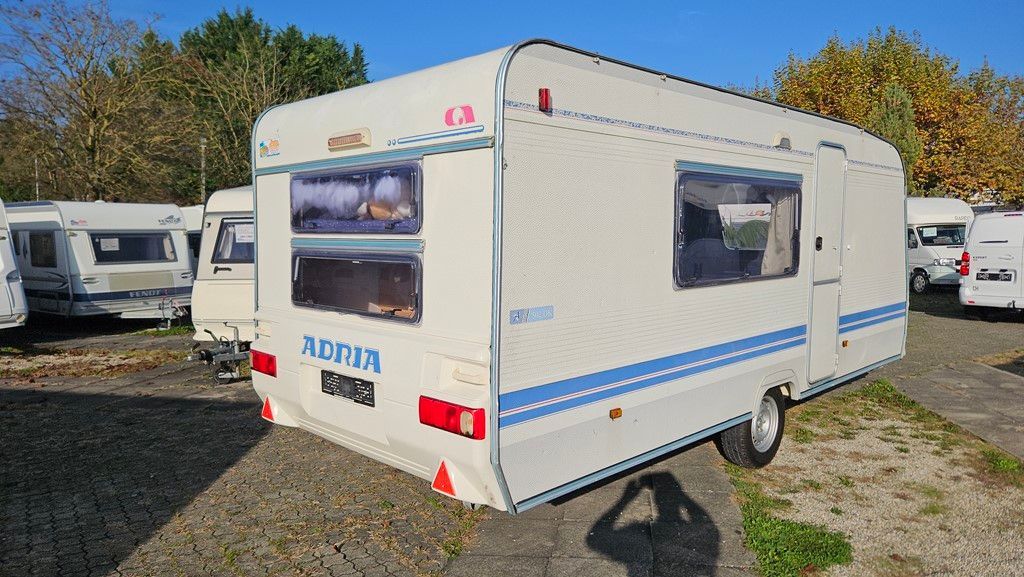 Une caravane blanche est garée sur un terrain en gravier.