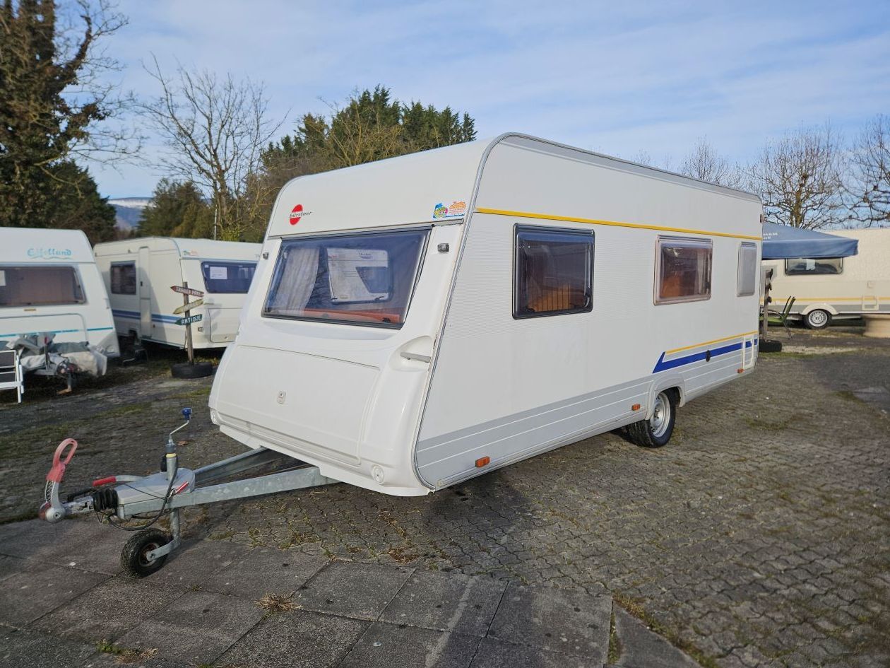 Caravane blanche avec logo rouge, garée à l'extérieur.