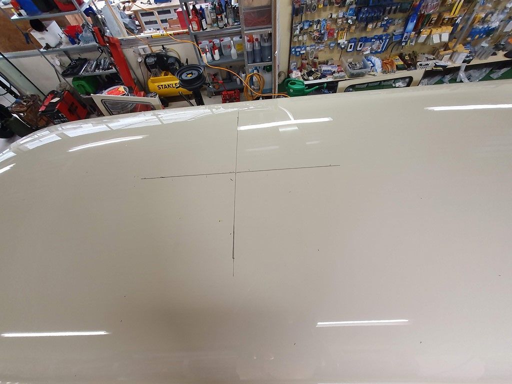 Un capot de voiture blanc est posé sur une table dans un garage.