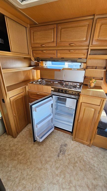 Une cuisine dans un camping-car avec un réfrigérateur et une cuisinière.