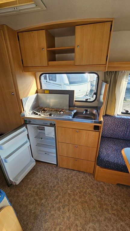 Une cuisine dans un camping-car avec un évier, une cuisinière, un réfrigérateur et des armoires.