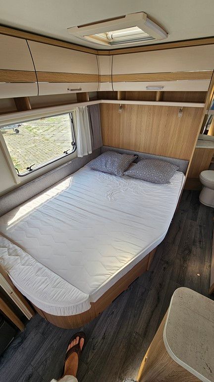 Une personne se tient à côté d'un lit dans un camping-car.