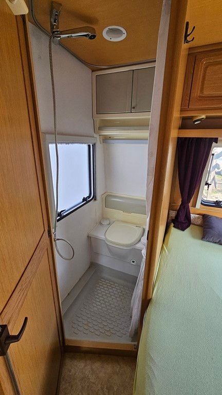 Une salle de bain dans un camping-car avec WC et douche.