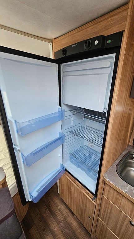 Un réfrigérateur dans un camping-car avec la porte ouverte.