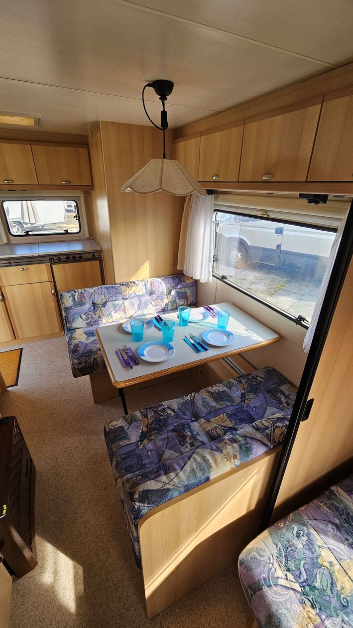 Un camping-car avec une table et un canapé à l'intérieur.