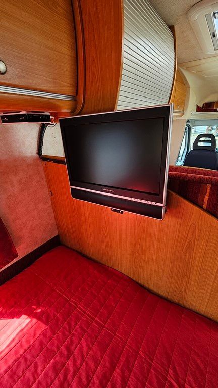 Un téléviseur à écran plat est suspendu au plafond d'un camping-car.