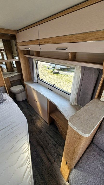 Un camping-car avec un lit, un bureau, des toilettes et une fenêtre.