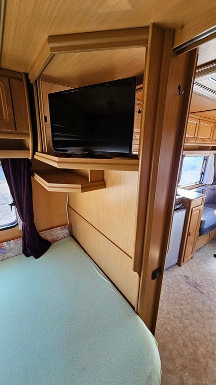 Une chambre dans un camping-car avec un lit et une télévision écran plat.