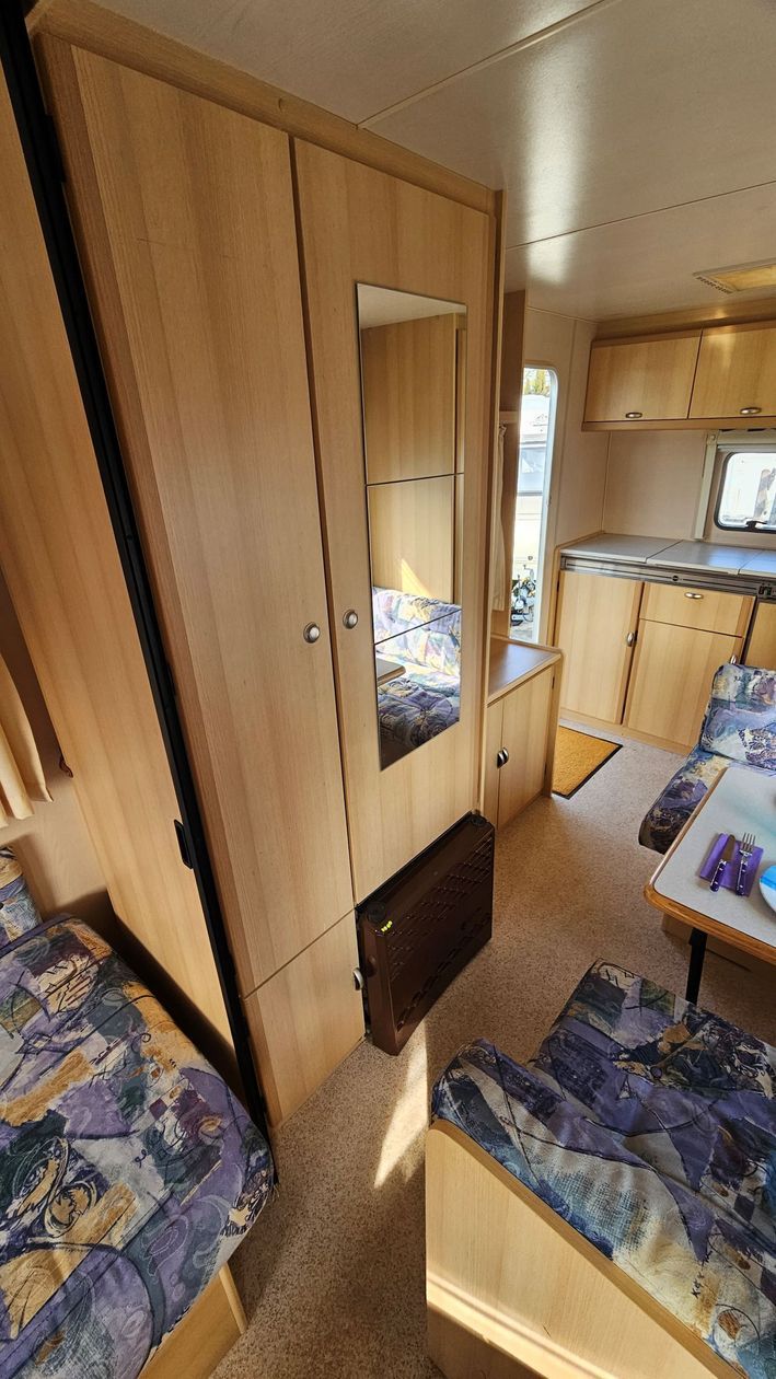 Un camping-car avec un lit, un canapé, une table et un miroir.