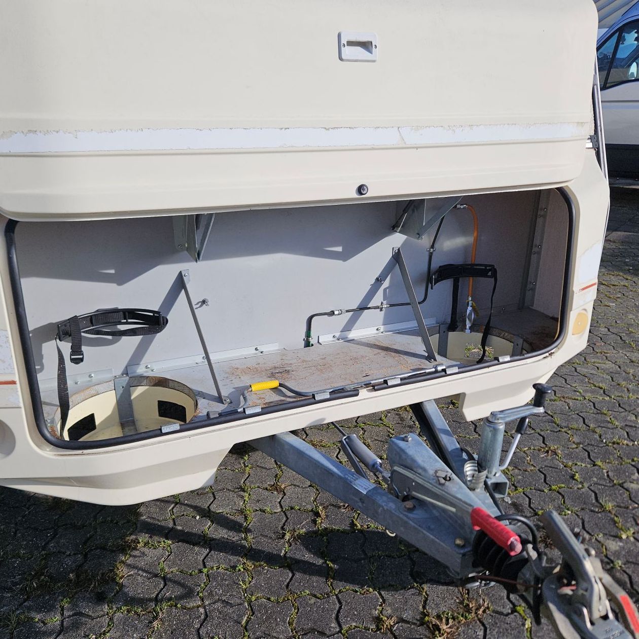 Compartiment de rangement ouvert sur une caravane couleur crème.