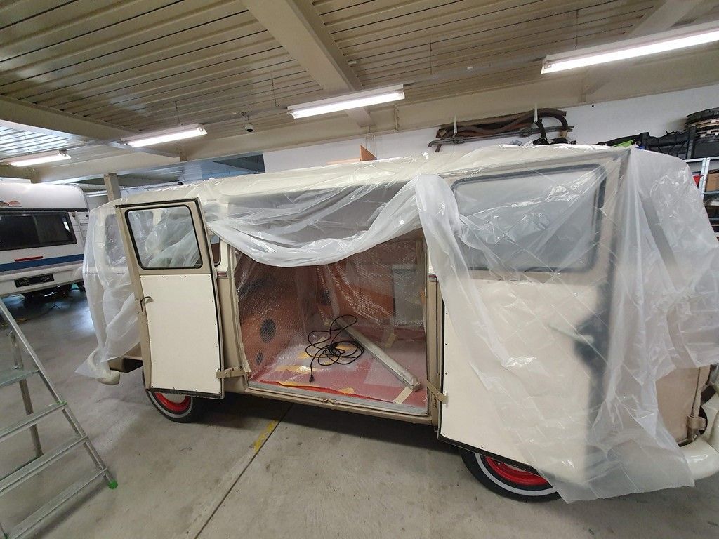 Une camionnette blanche est recouverte d'une pellicule plastique dans un garage.
