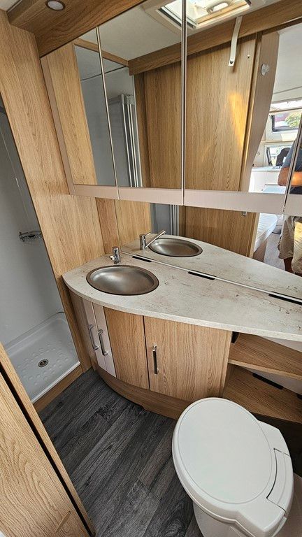 Une salle de bain dans un camping-car avec WC, lavabo et miroir.