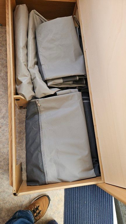 Une personne se tient à côté d'un tiroir rempli de vêtements.