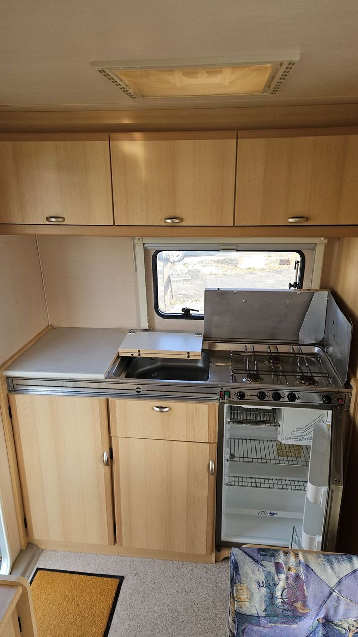 Une cuisine dans un camping-car avec un évier, une cuisinière et un réfrigérateur.