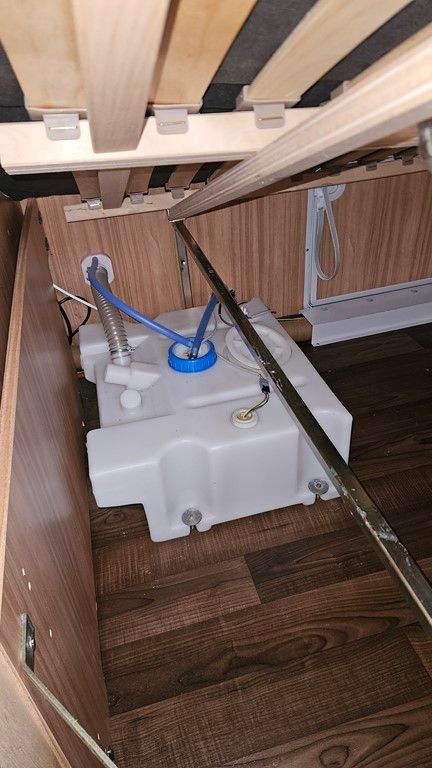 Un réservoir d'eau se trouve sous un lit dans un camping-car.