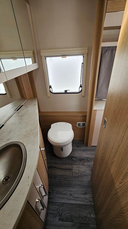Une salle de bain dans un camping-car avec WC, lavabo et miroir.