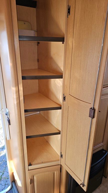 Une armoire en bois avec étagères et portes dans un camping-car.
