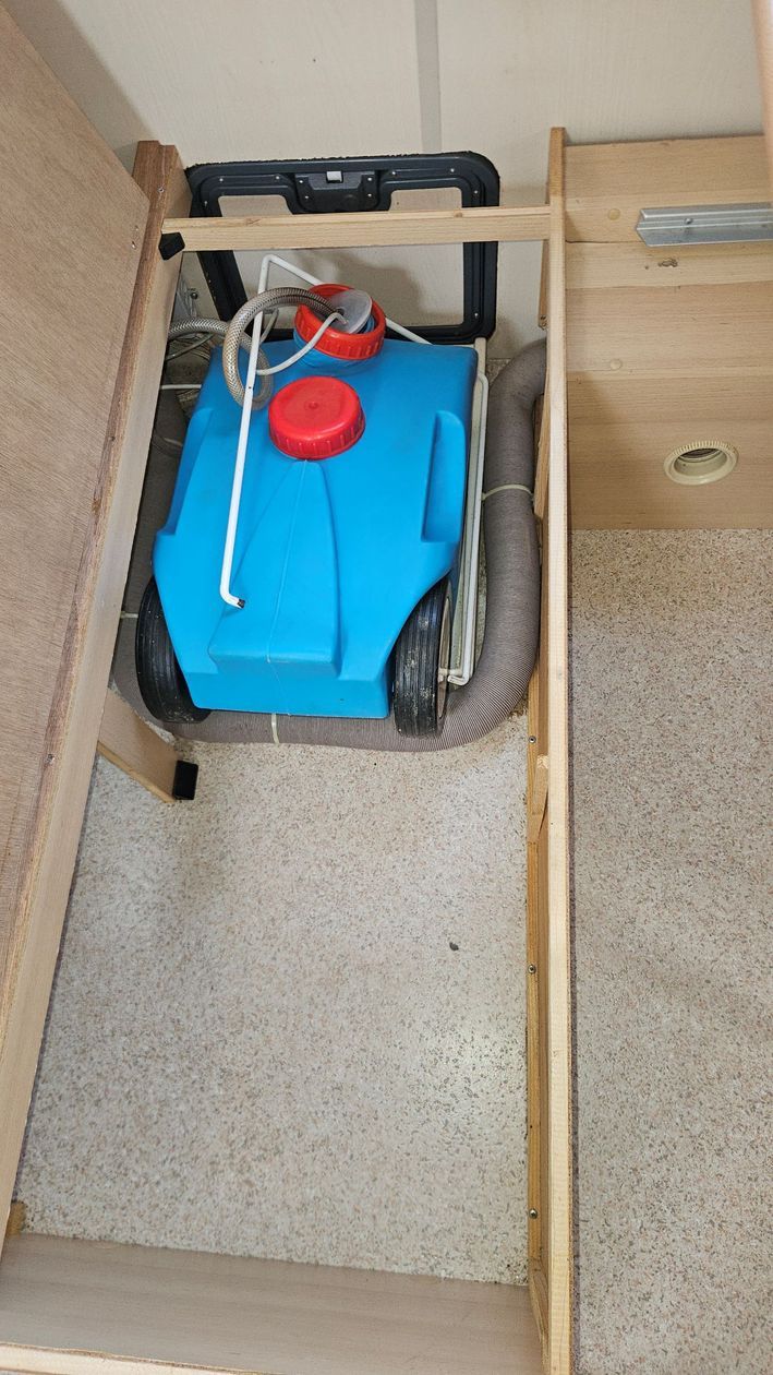 Un réservoir bleu est assis sous une étagère en bois dans une pièce.