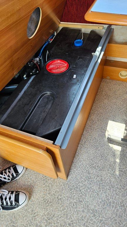 Une personne se tient à côté d'un tiroir contenant un réservoir d'eau.