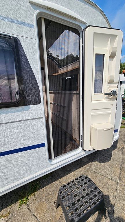 Une caravane blanche avec la porte ouverte et une marche.