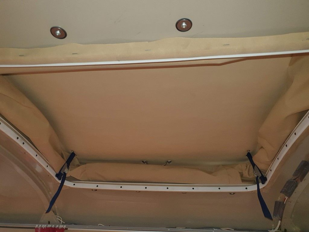 Le plafond d'un camping-car est recouvert d'une couverture beige.