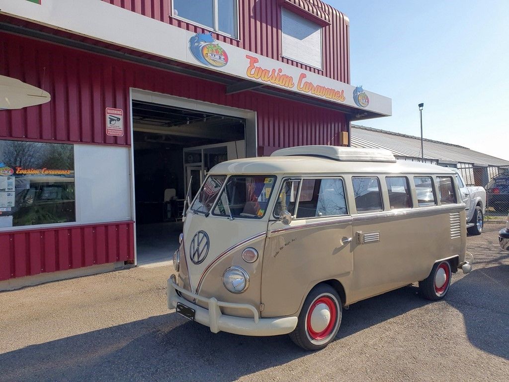 Une camionnette beige est garée devant un bâtiment rouge.