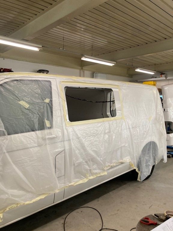 Une camionnette blanche est en train d'être peinte dans un garage.