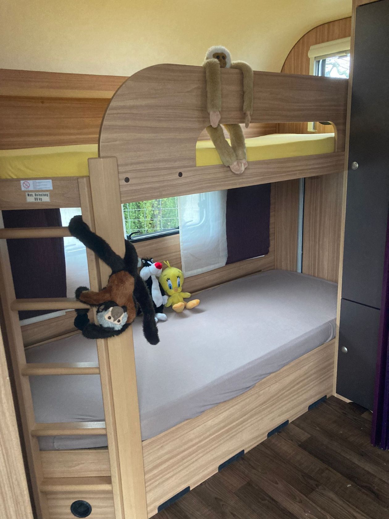 Un lit superposé avec des animaux en peluche dessus dans un camping-car.