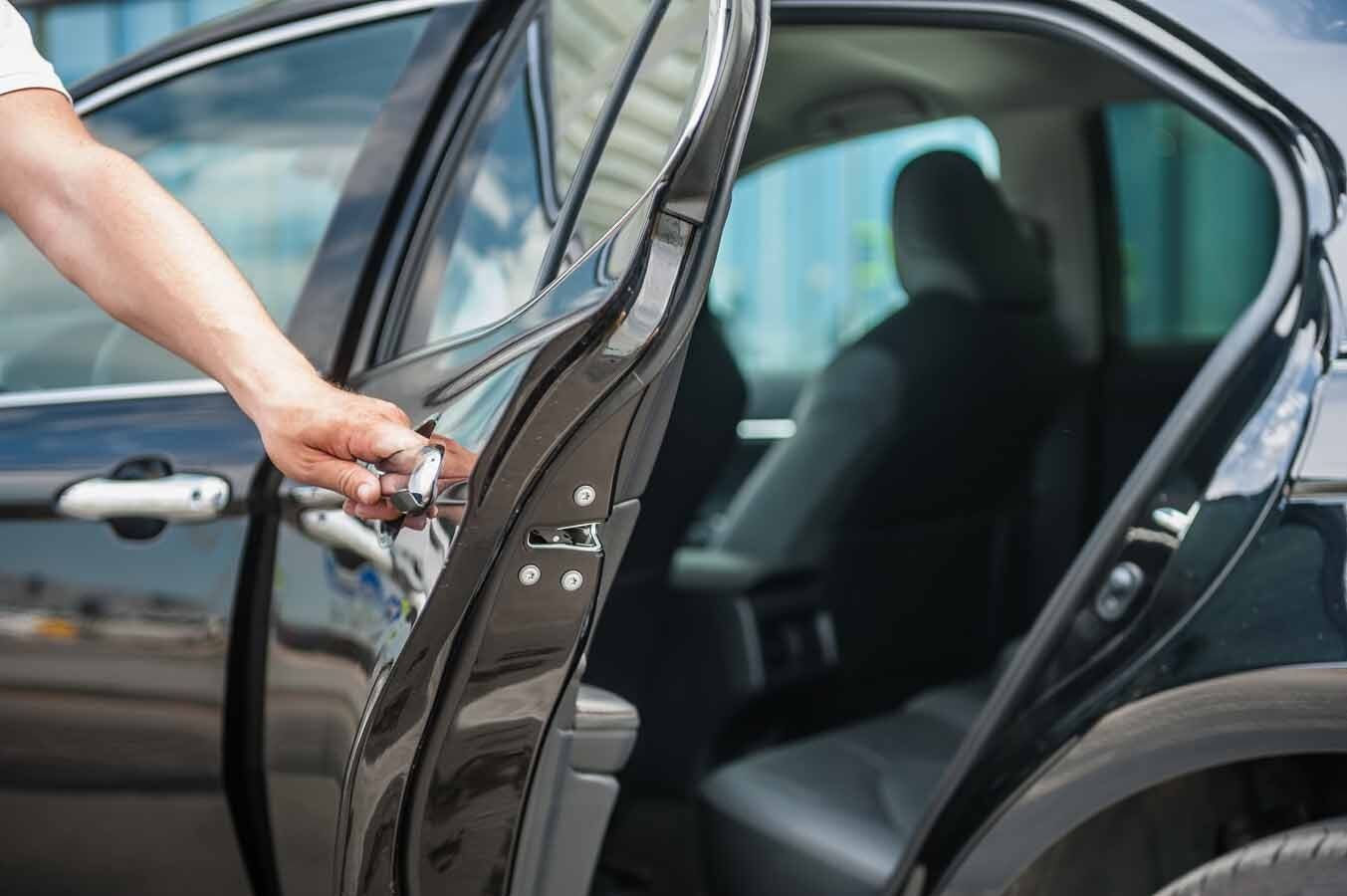 Personne tenant ouverte la porte d'un taxi noir