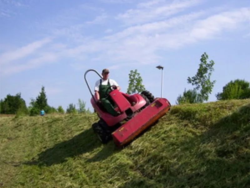 Ein Mann fährt mit einem Rasenmäher einen Hügel hinauf