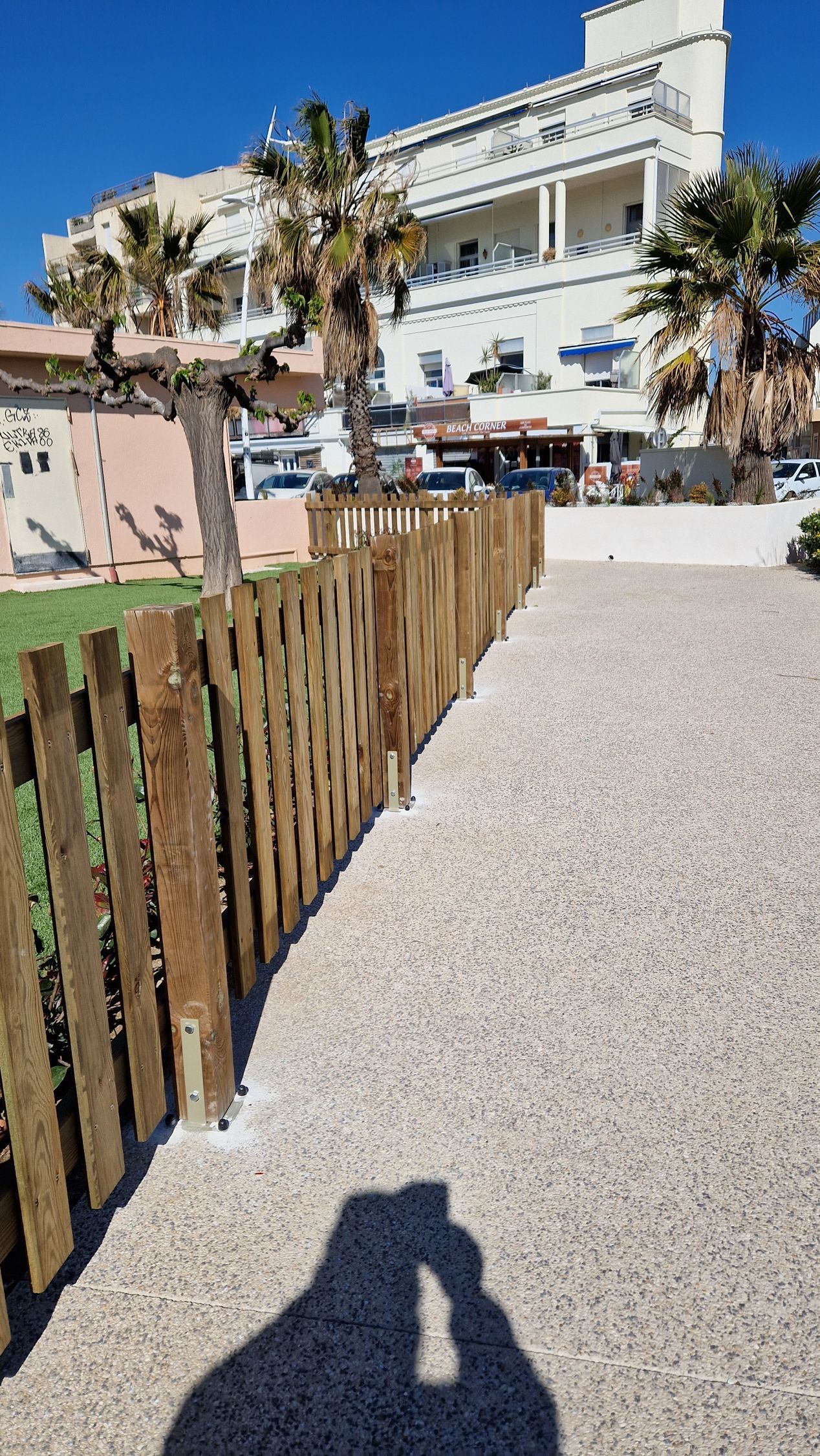 Clôture en bois entre une pelouse et une allée de gravier