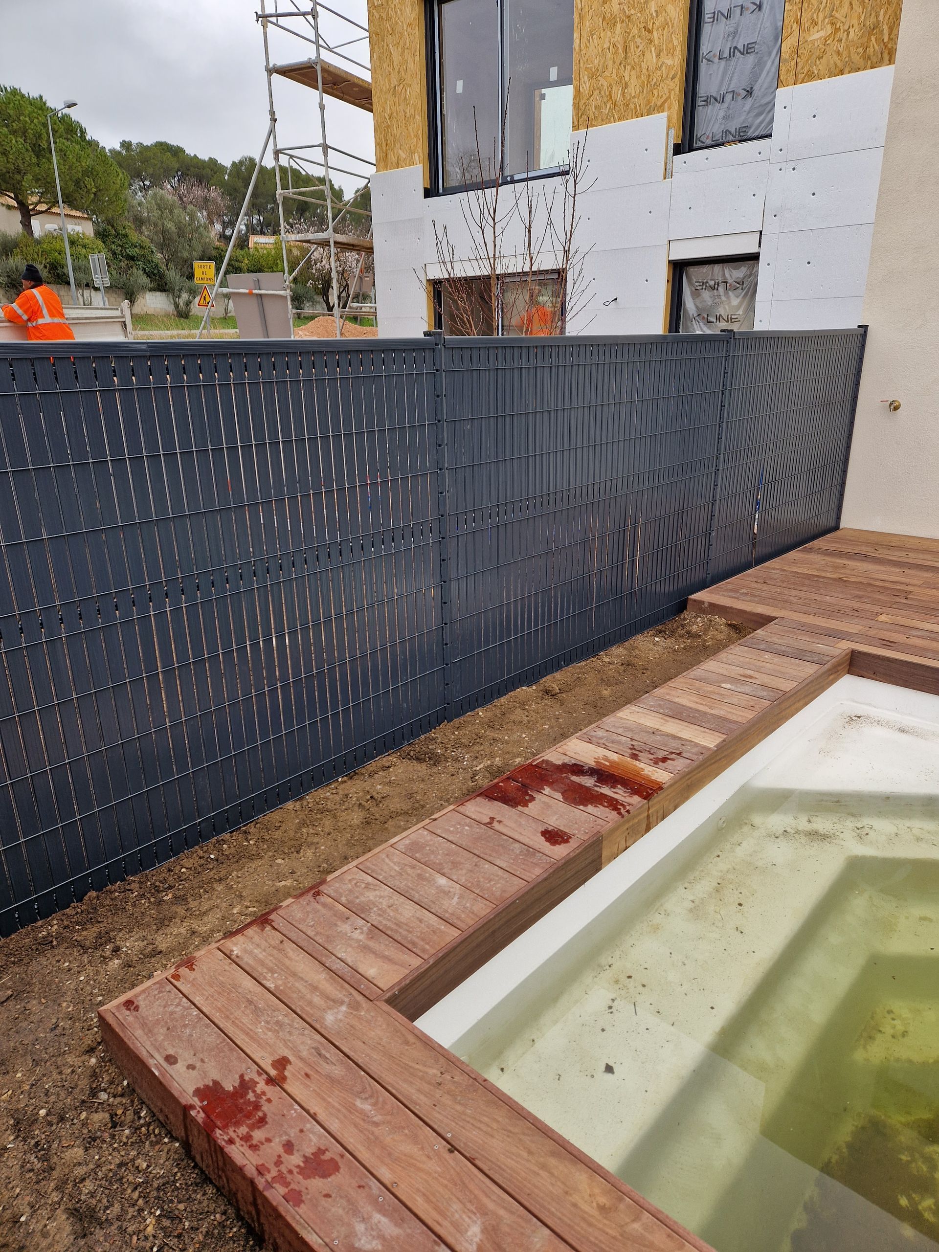 Claustra en PVC noir devant une terrasse en bois et une piscine