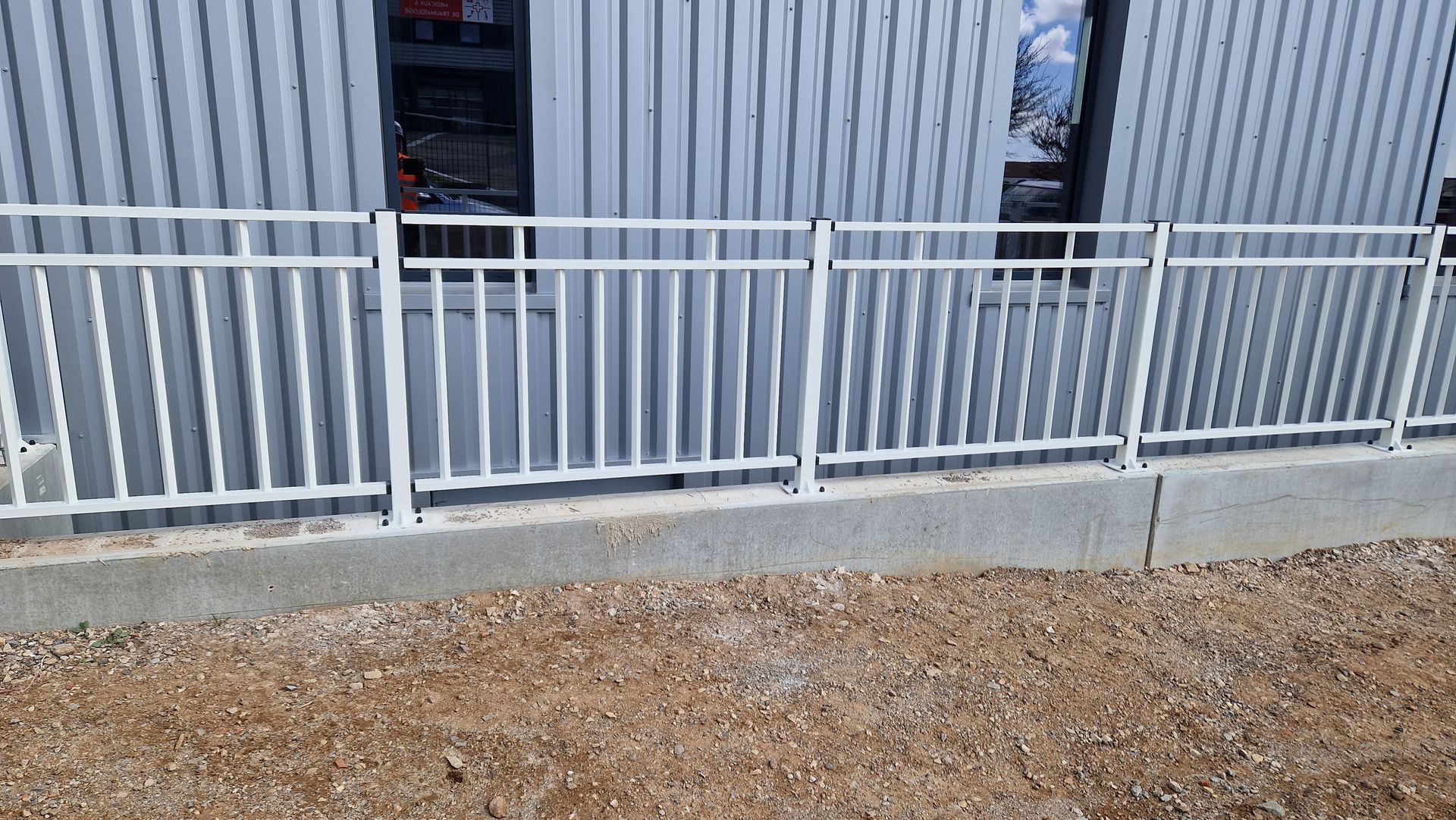 Clôture blanche sur un muret en béton