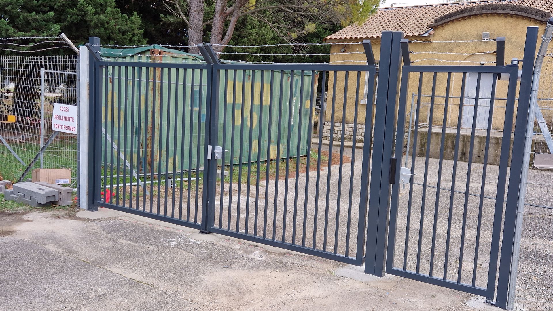 Portail à deux vantaux en PVC avec fils de fer barbelés au-dessus