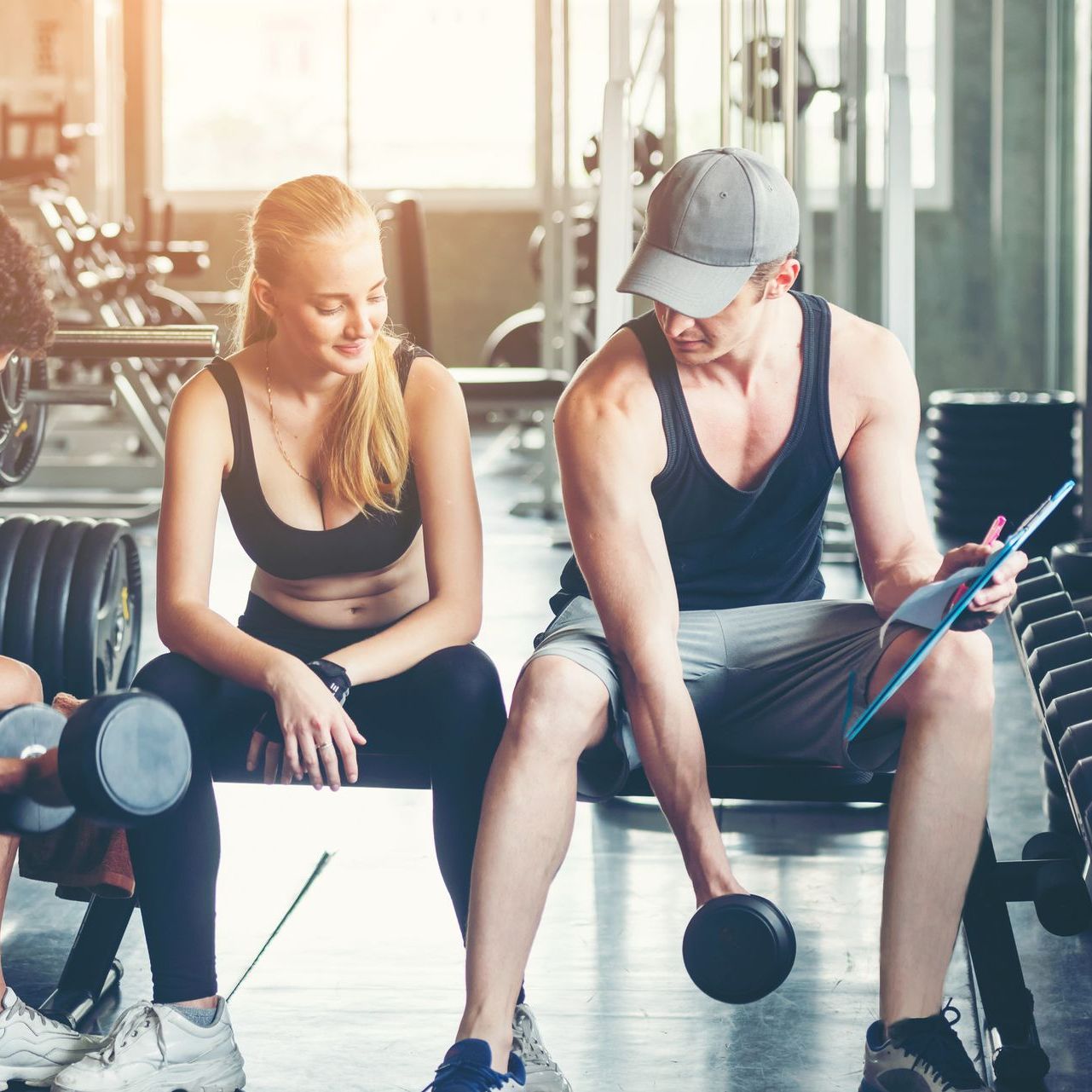 Un hombre y una mujer están sentados en un banco en un gimnasio.