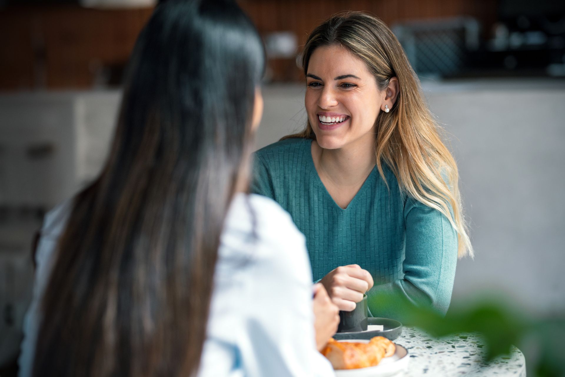 Dos mujeres están sentadas en una mesa hablando entre sí.