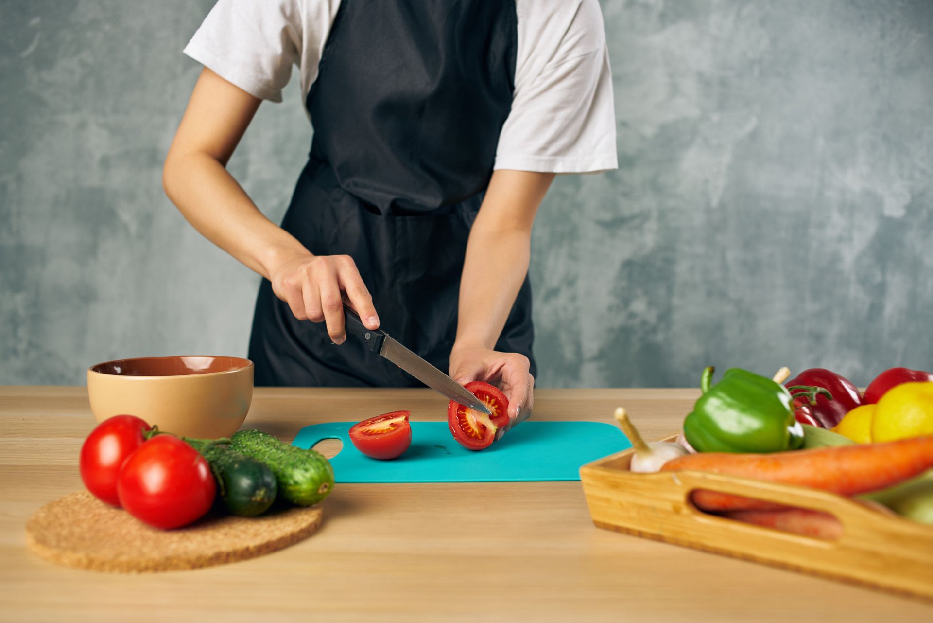 Una mujer está cortando un tomate en una tabla de cortar.