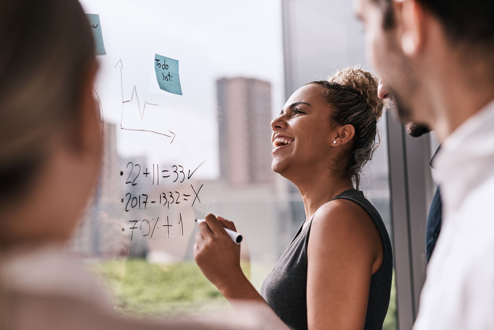 Una mujer está escribiendo en una pizarra delante de un grupo de personas.