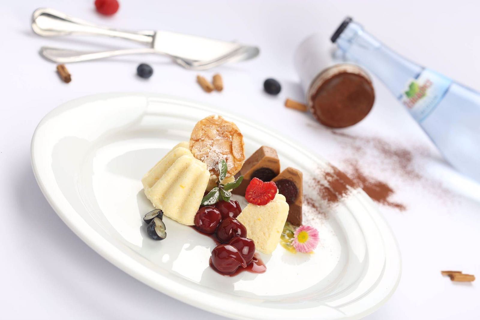 ansprechend angerichteter Dessertteller mit kleinem Gugelhupf, Kirschen und zwei Schokodessert-Elementen