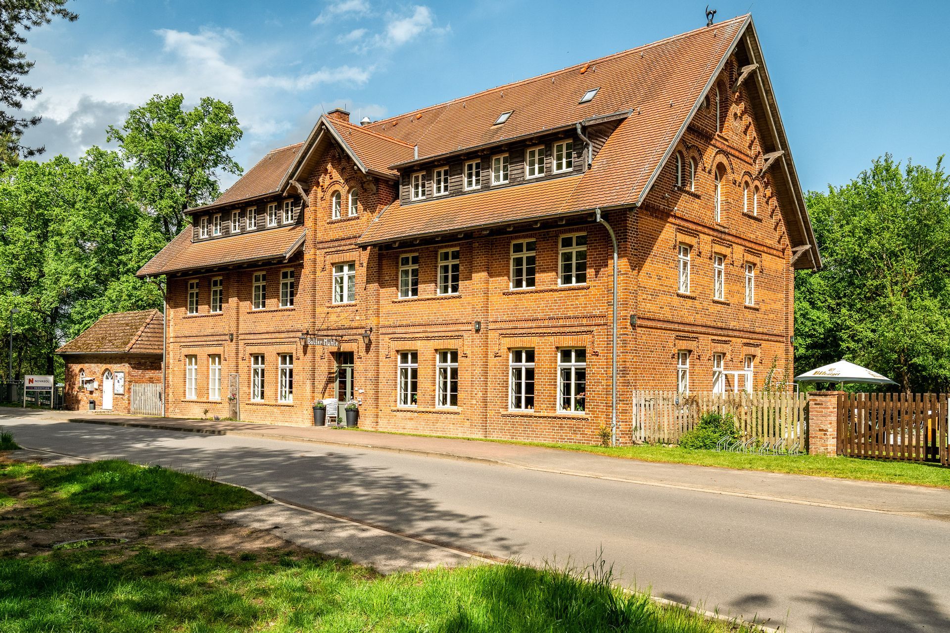 Großes Fachwerkhaus aus Ziegeln mit rotem Ziegeldach an einer ruhigen Straße unter blauem Himmel