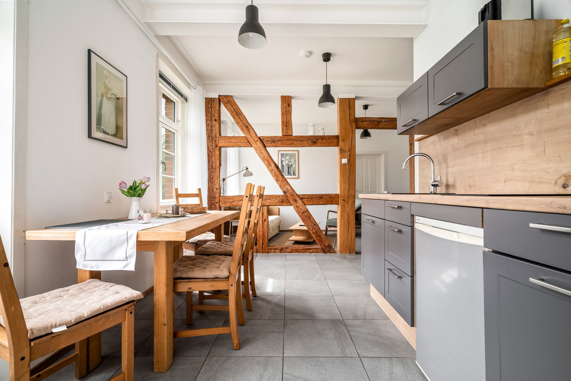 Helle, moderne Küche mit grauen Schränken, Holzelementen, Esstisch und Oberlicht.