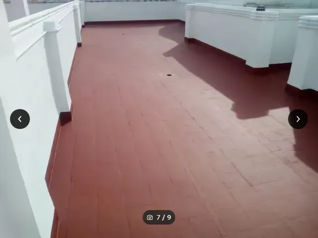 Habitación vacía con suelo rojo y encimeras o armarios blancos a lo largo de las paredes.