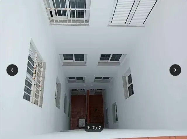 Al mirar hacia arriba, se ve un atrio blanco abierto con ventanas y una puerta de madera debajo.